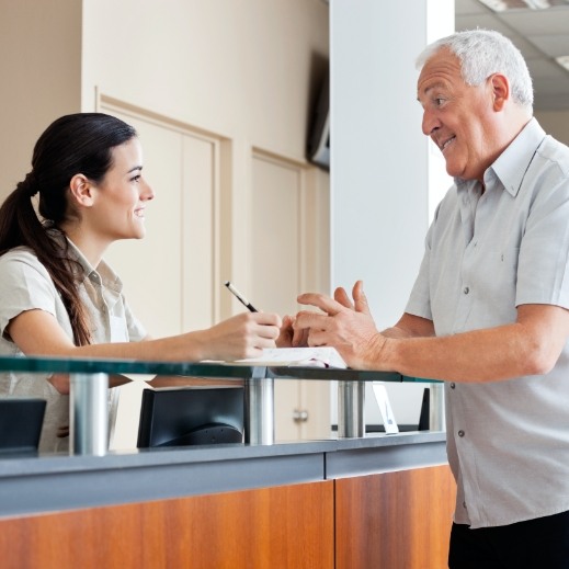 Man turning in dental insurance paperwork at reception desk